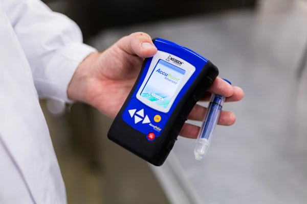Neogen AccuPoint Advanced ATP testing device being used to verify surface cleanliness in a food processing facility.